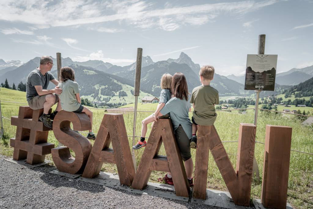 Familie sitzt auf Holzbuchstaben Saani