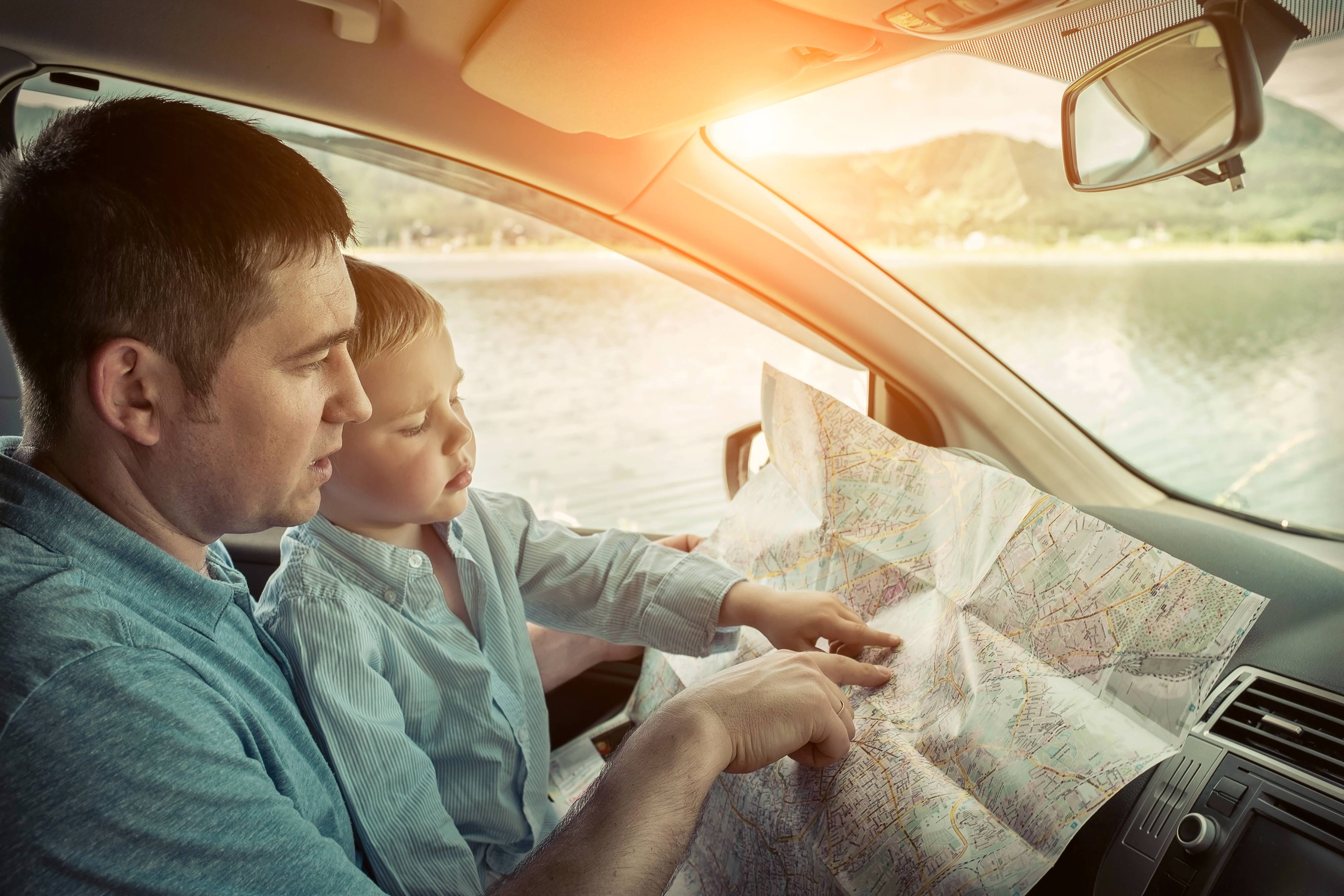 Vater mit Kind liest eine Karte im Auto