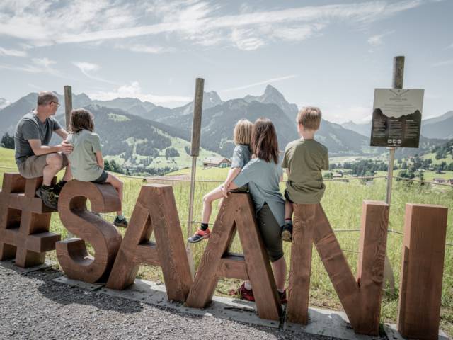 Familie sitzt auf Holzbuchstaben Saani