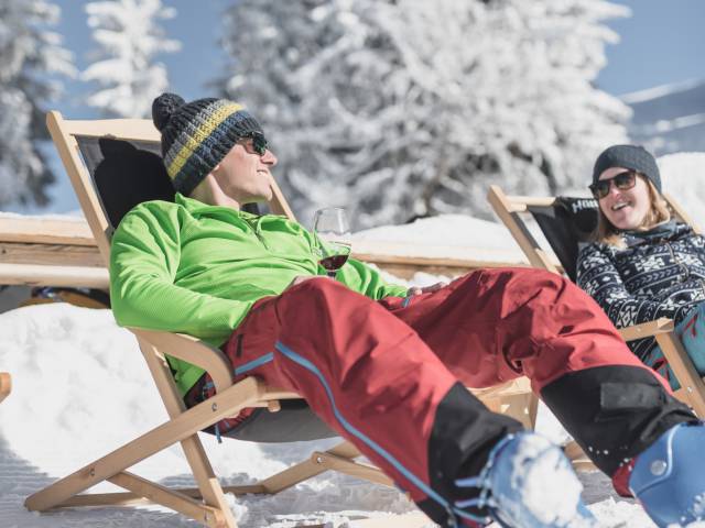 Mann und Frau in Liegestühlen im Schnee in Gstaad