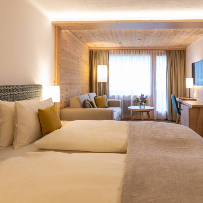 Doppelzimmer mit Couch und TV im Hotel Gstaaderhof in der Schweiz