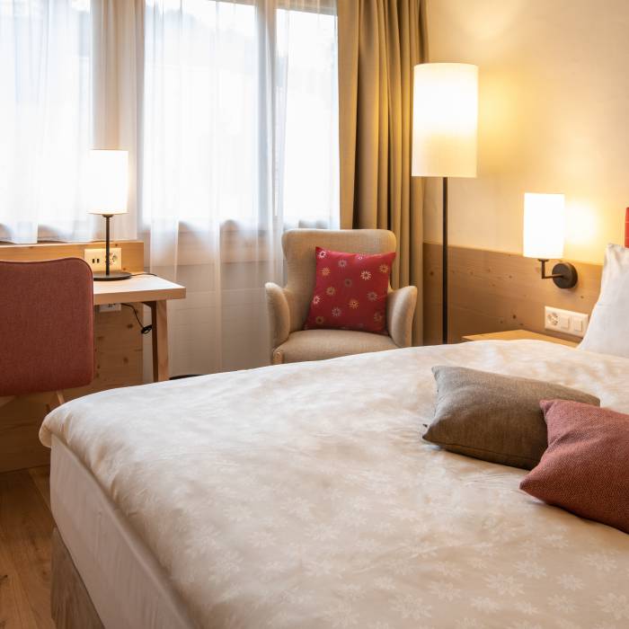 Doppelzimmer mit Sessel und Tisch im Hotel Gstaaderhof