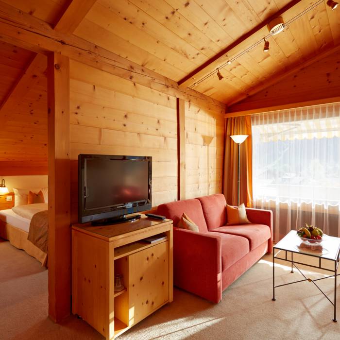 Familienzimmer mit Couch und Balkon im Hotel Gstaaderhof