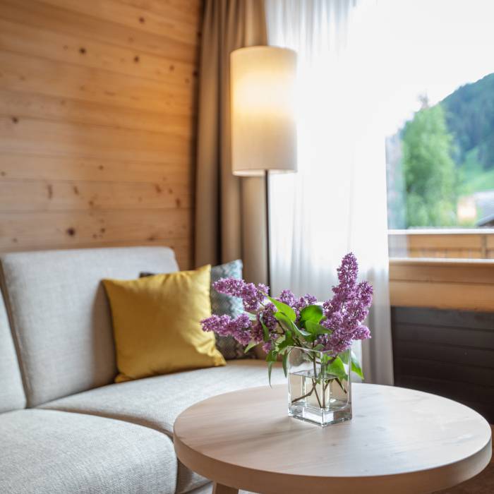 Couch und Tisch mit frischem Flieder im Hotel Gstaaderhof