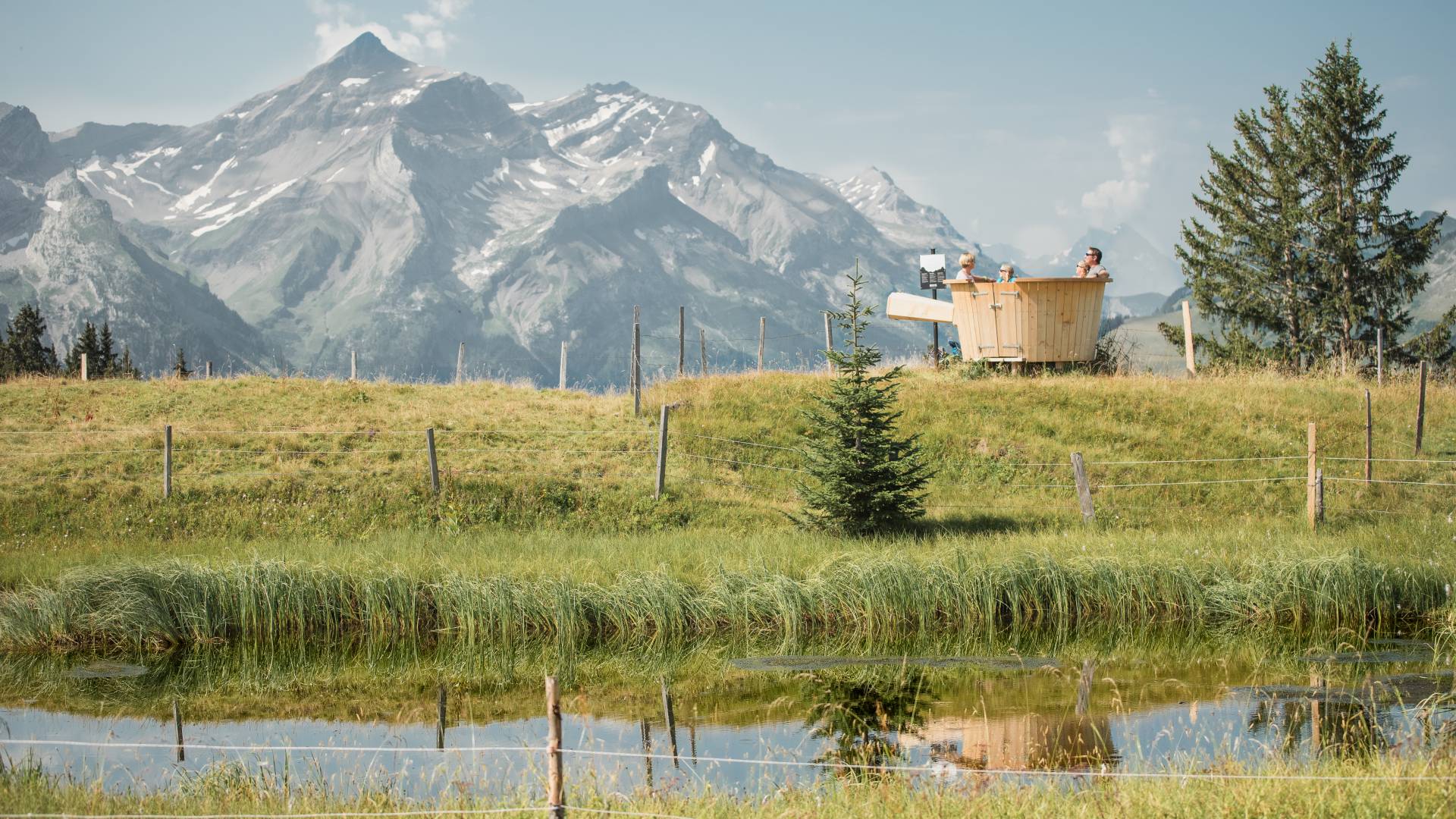 Paar beim Baden im Holzfass mit Blick auf die Schweizer Berge